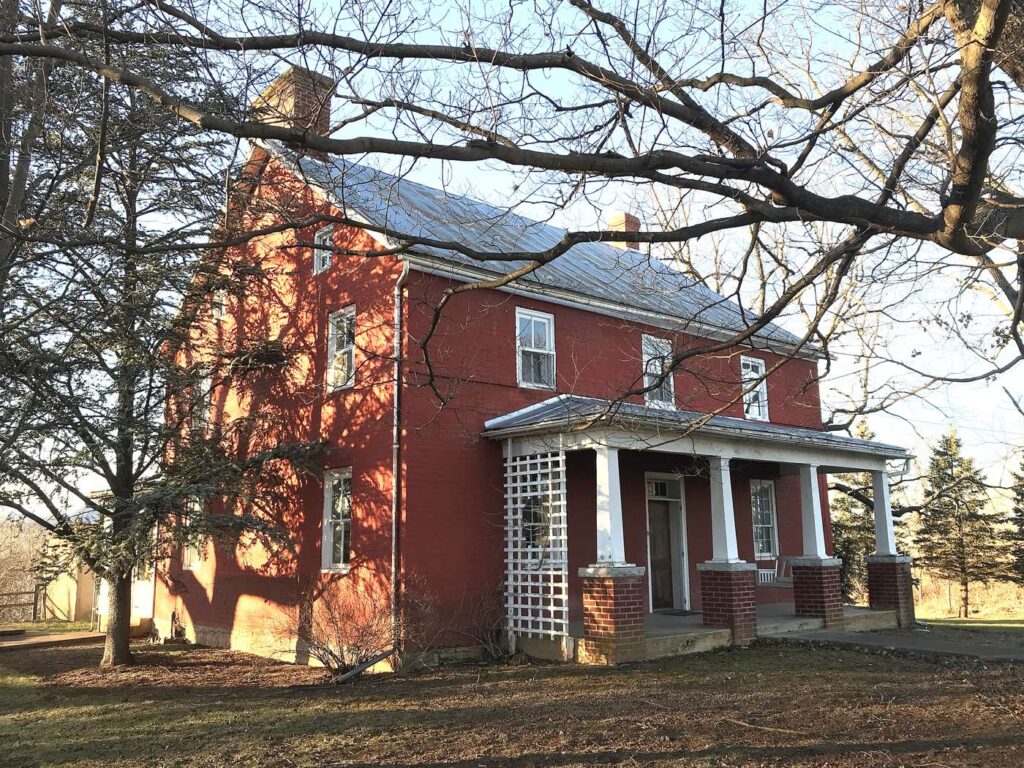 Red brick Elder John Kline house with a white front porch